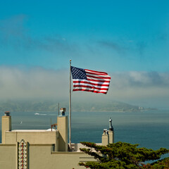 The American flag flutters over San Francisco Bay as the fog approaches: it hangs suspended in the sky. San Francisco, California, USA.