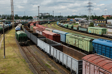 Freight train cars of various colors are lined up in a railway yard, surrounded by green grass and...
