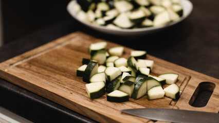 Sliced zucchini on a wooden cutting board, with a knife, in the kitchen, ready to be used in a healthy meal