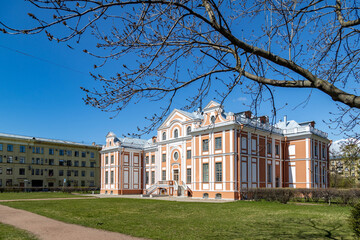 The historic baroque-style Kikiny Chamber on a green lawn, framed by a budding tree branch in...