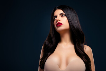 Fabulous brunette woman in stylish attire posing against a dark gradient background, showcasing...