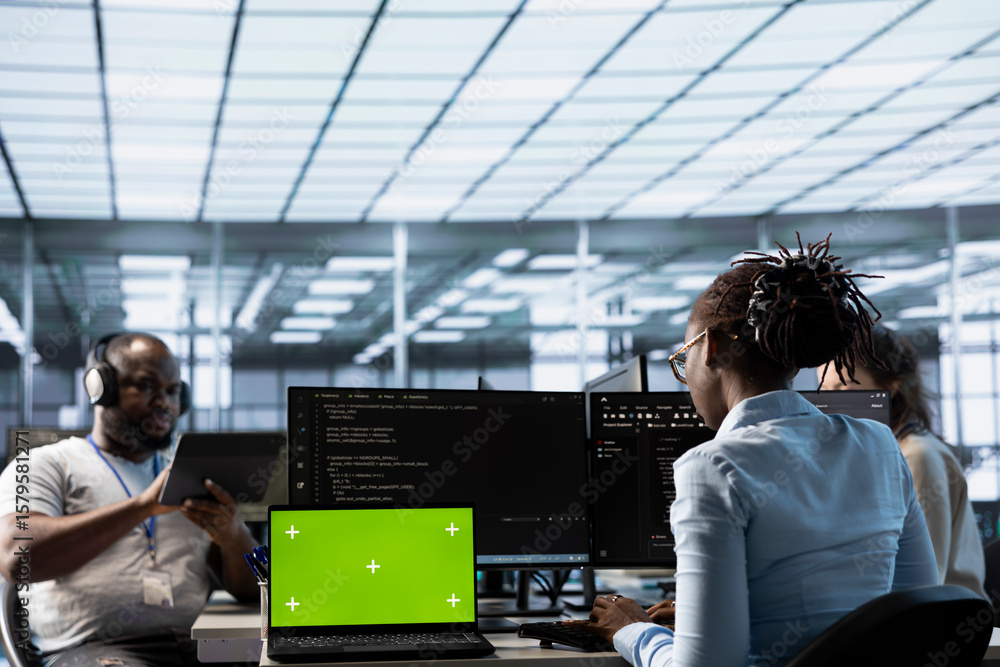 Poster green screen laptop in data center in front of it support specialists working together, supervising 