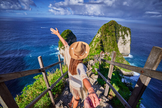 Follow me to scenic Kelingking beach. Traveling couple on vacation journey holiday to Nusa Penida Island in Indonesia, explore and travel to touristic beautiful destinations, honeymoon together