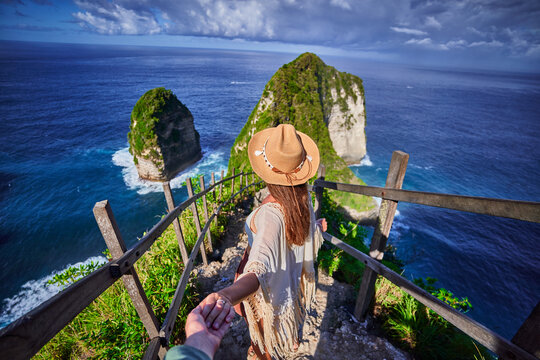 Follow me to scenic Kelingking beach. Traveling couple on vacation journey holiday to Nusa Penida Island in Indonesia, explore and travel to touristic beautiful destinations, honeymoon together