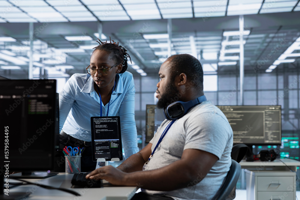 Poster technician requesting help from manager while working on computer in data center, monitoring hardwar