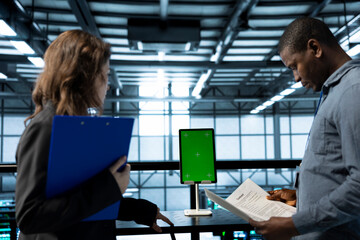 Inspector checking documents in server hub to ensure compliance with industry standards and using...