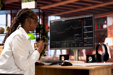 Happy day trader gaining money by selling stocks after browsing through documents to learn how to maximize profits. Ecstatic investor celebrating financial gains earned from stock exchange