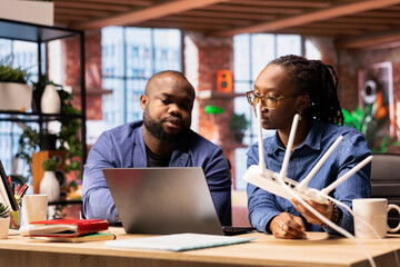 African American woman pulling out the LAN cable from the router while her partner reads a...