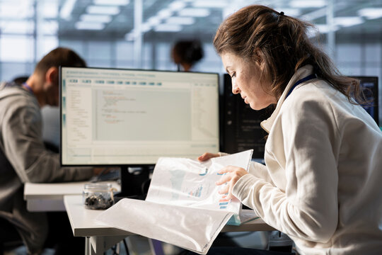 Inspector checking documents in server hub to ensure compliance with industry standards and regulatory requirements. Admin inspecting files, overseeing data center workplace security protocols