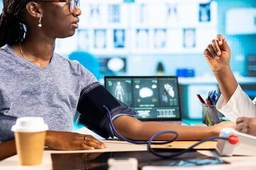 Woman medic expert measuring blood pressure at a consultation with patient, using blood pressure...