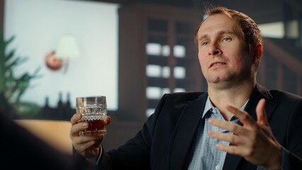 Elite society member doing negotiations with a partner over blended whiskey at a vintage country...
