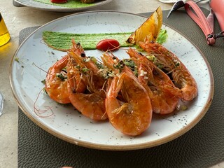 Roasted fried big shrimps in tomato sauce with olive oil, garlic, cilantro and soy sauce