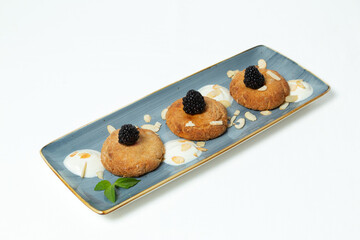 Homemade cookies topped with blackberry, almond flakes, and honey on a plate against a white background