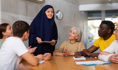 Friendly interested young Asian female student in traditional muslim black dress and khimar...