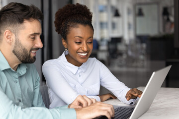 African female manager showing presentation on laptop to company client during formal meeting or...