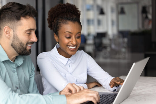 African female manager showing presentation on laptop to company client during formal meeting or negotiations in modern meeting room. Two colleagues reviewing new AI program or platform in workplace - Powered by Adobe