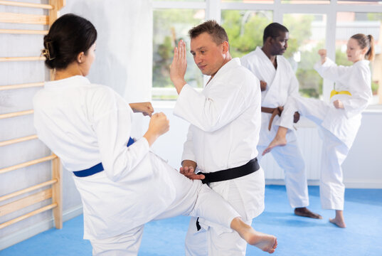 Multinational partners during martial arts karate class train to perform basic blows to opponent with hands and feet. Preparation of athletes for competitions