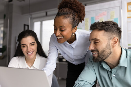 Three multiracial workmates, team members brainstorm ideas for business campaign, analyze customer feedback, improve services, working together during meeting in office using modern laptop, close up - Powered by Adobe