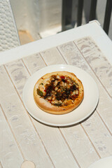 Freshly baked mini pizzas on a rustic wooden table, topped with melted cheese, basil, and vibrant toppings, creating a cozy, homemade vibe