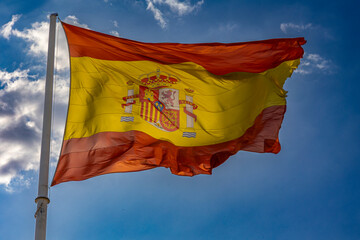 Flag of Spain Waving in the Wind Against a Blue Sky Background