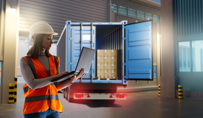 Female logistics coordinator in safety gear using laptop to manage cargo shipment from open container truck at warehouse. - Logistics. Shipping. Warehouse.