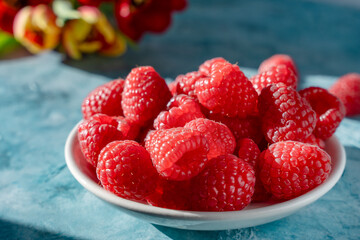 Bowl Of Ripe Raspberries On Blue Tabletop