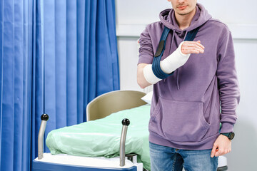 Man With Broken Arm In Cast Standing By Hospital Bed