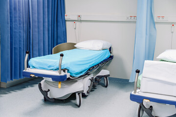 Empty Hospital Bed, Separating Blue Curtains In Ward