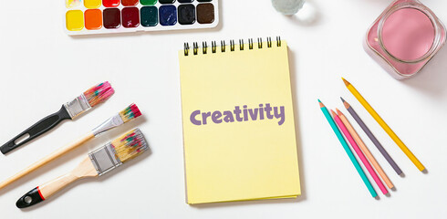 Notebook With Creativity Text And Colorful Art Tools Top VIew