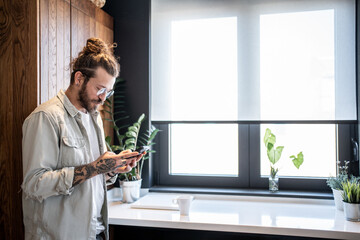 Young man using smartphone in modern kitchen