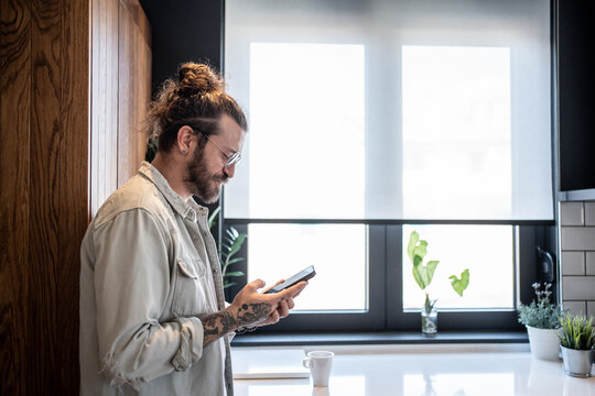 Freelancer using smartphone in modern kitchen during work from home day