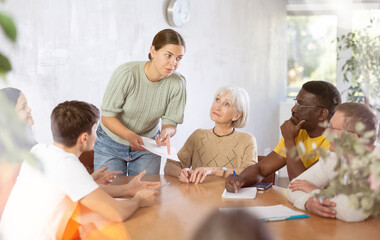 Interested friendly young girl, student of adult school, taking part in discussion of study topics...