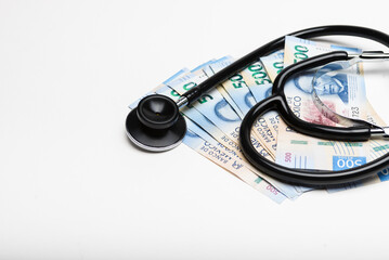 A stethoscope rests on a stack of 500 Mexican peso banknotes, high cost of healthcare