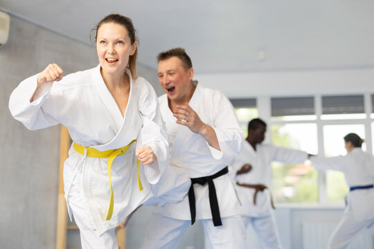 Adult man and adult woman judokas practicing judo technique in group in gym