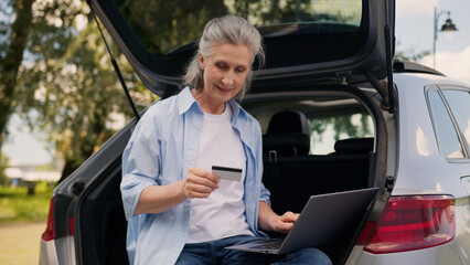 Happy Caucasian elderly woman female senior car driver sit auto trunk mature user client customer...