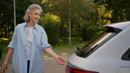 Happy elderly Caucasian shopper woman shopaholic female senior mature customer consumer automobile...