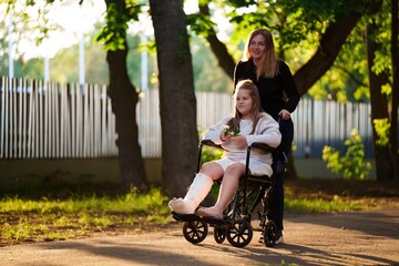 Girl with broken leg smiles from wheelchair as mom rolls her under golden sky. Touching scene for...