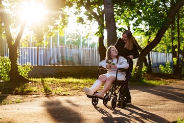 Broken leg is not problem. Girl in wheelchair enjoys park evening with mom. Great for motivational...