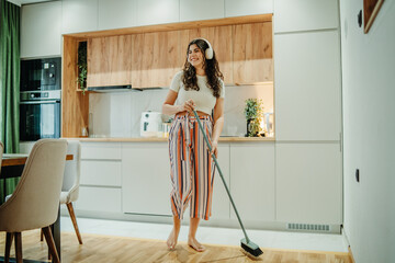 Young caucasian woman cleaning the house while listening to music