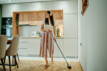 Young caucasian woman cleaning the house while listening to music