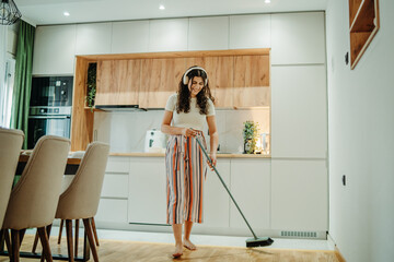 Young caucasian woman cleaning the house while listening to music