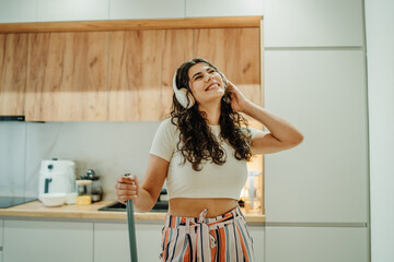 Young caucasian woman cleaning the house while listening to music