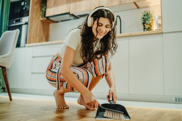 Young caucasian woman cleaning the house while listening to music