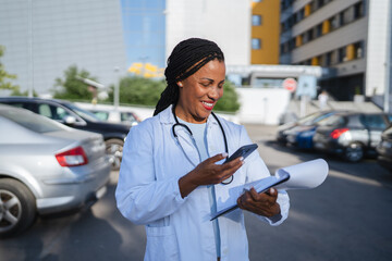 african american woman doctor hold cellphone and scan document outdoor
