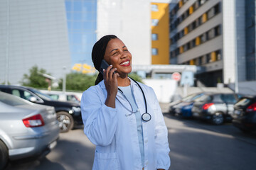 african american woman doctor talk on mobile phone in front hospital