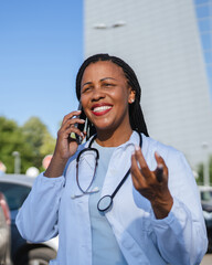 african american woman doctor talk on mobile phone in front hospital