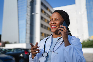 african american woman doctor talk on mobile phone in front hospital