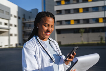 african american woman doctor hold cellphone and scan document outdoor