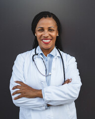 Portrait of african american woman doctor stand in front black wall