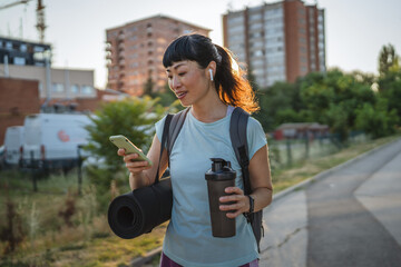 japanese woman drink protein shake and use mobile phone go to training